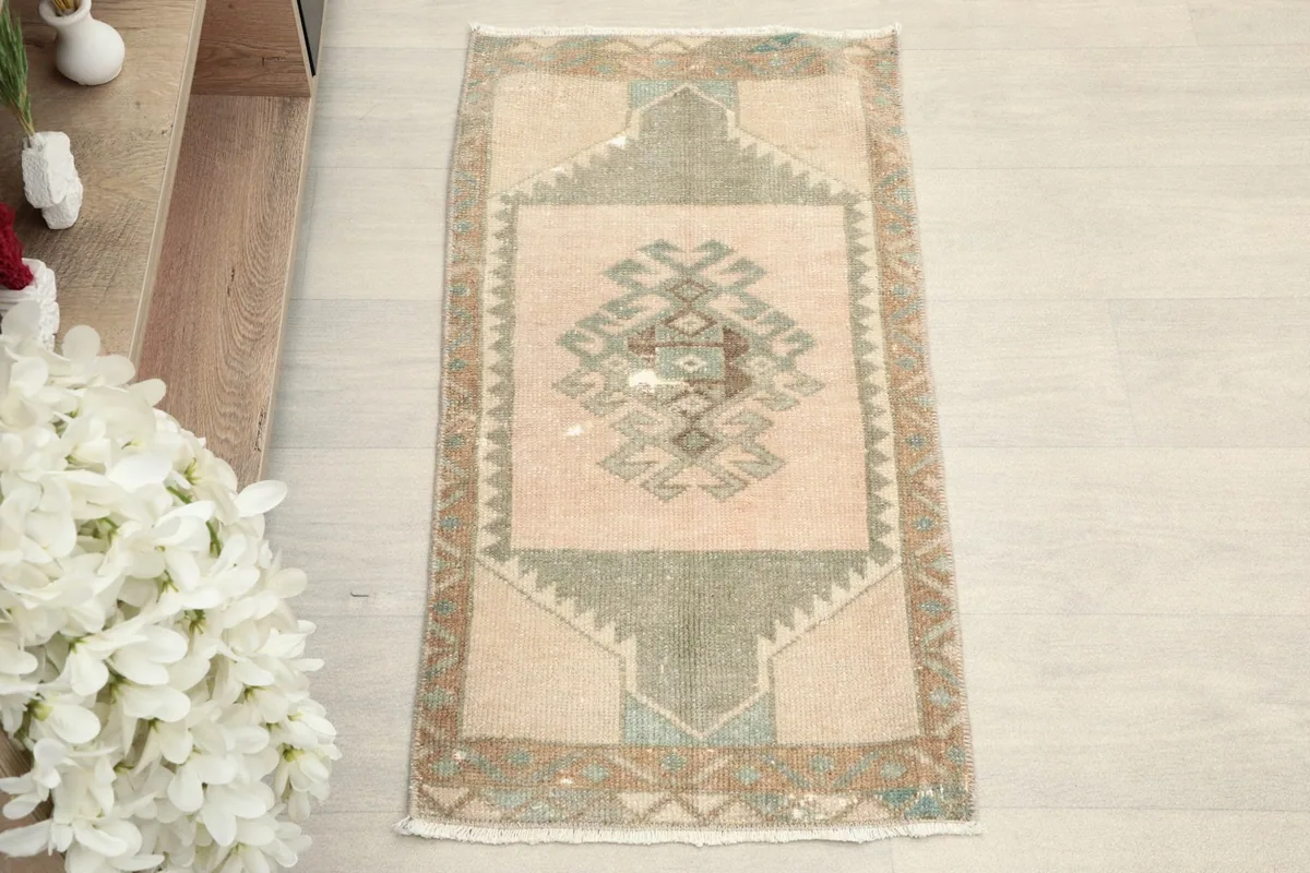 Overhead view of the small beige rug with its central green geometric design