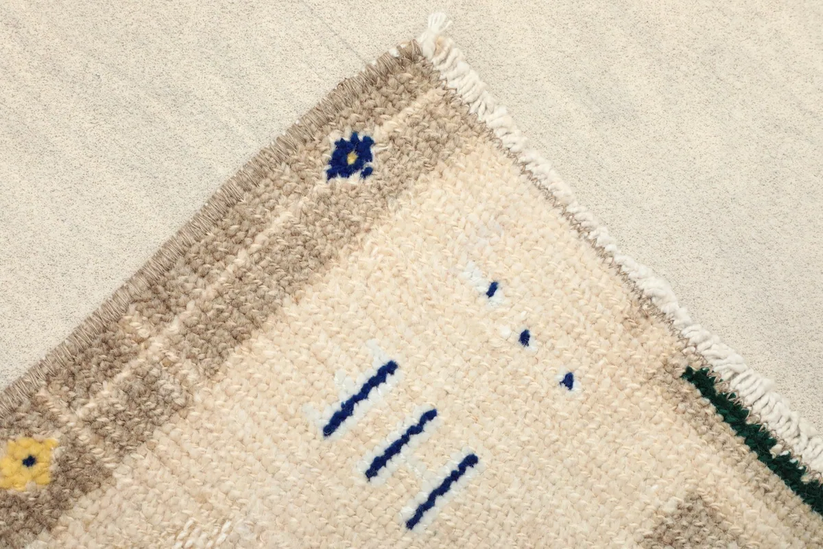 Detailed corner shot showing the beige field, brown border, and small navy and yellow accents.