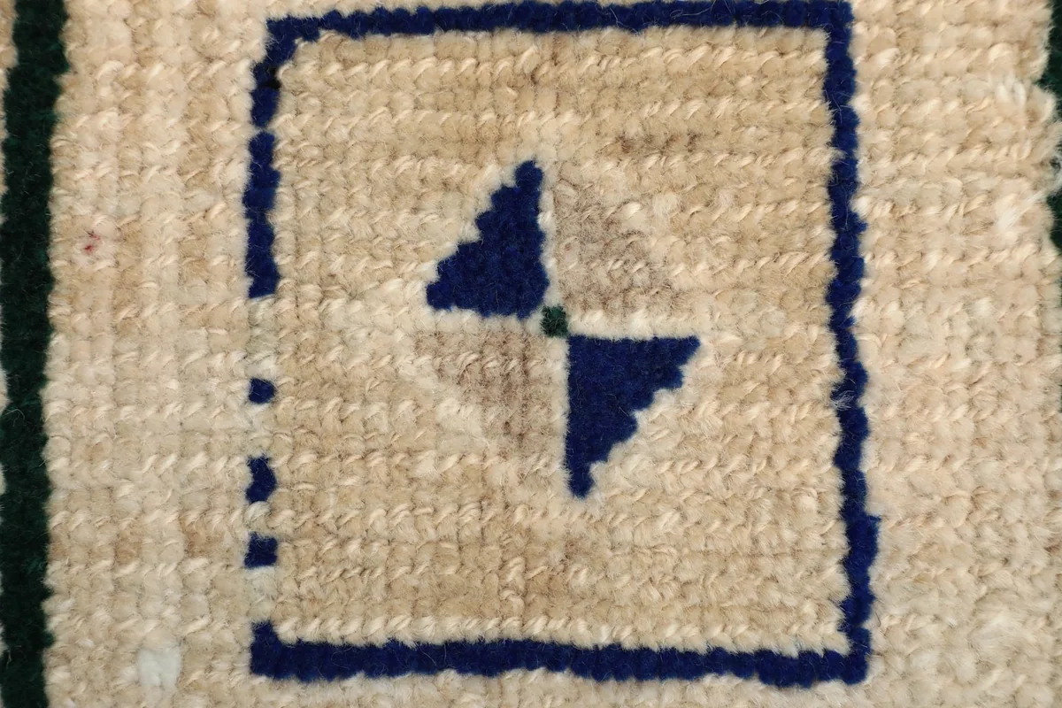 Extreme close-up of the low wool pile and a central navy geometric motif.