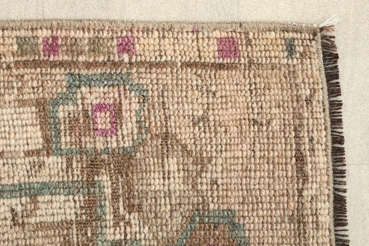 Close-up of the rug's edge, revealing the hand-knotted wool pile and subtle color variations.