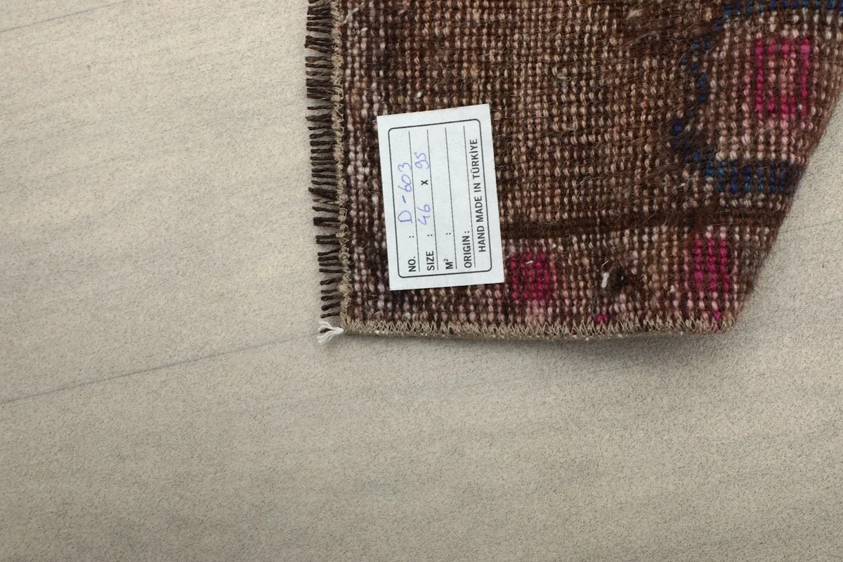 Close-up of the rug's back, revealing the hand-knotted construction and a product tag.