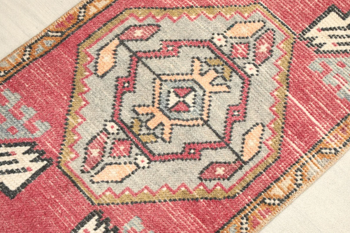 Close-up of the central gray medallion with rose, orange, and black geometric motifs.