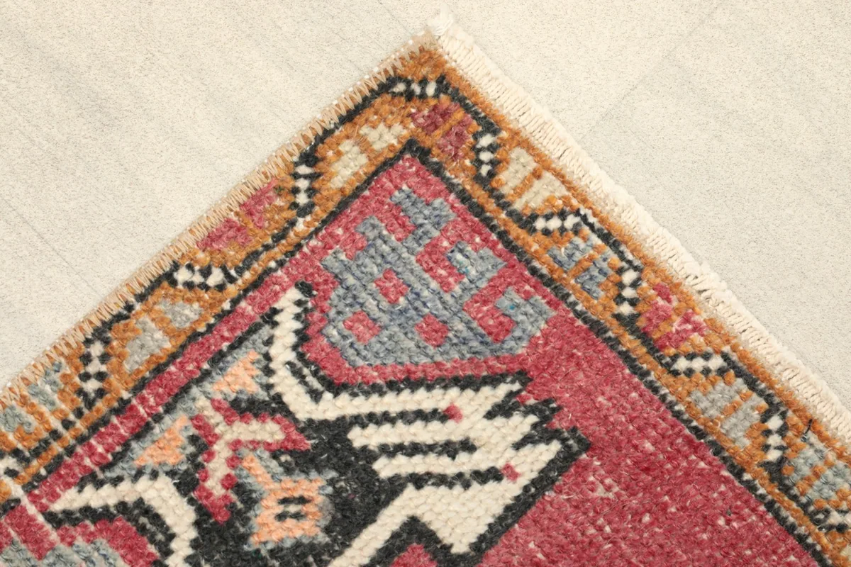 Corner detail of the rug showing the tan and black patterned border and short fringe.