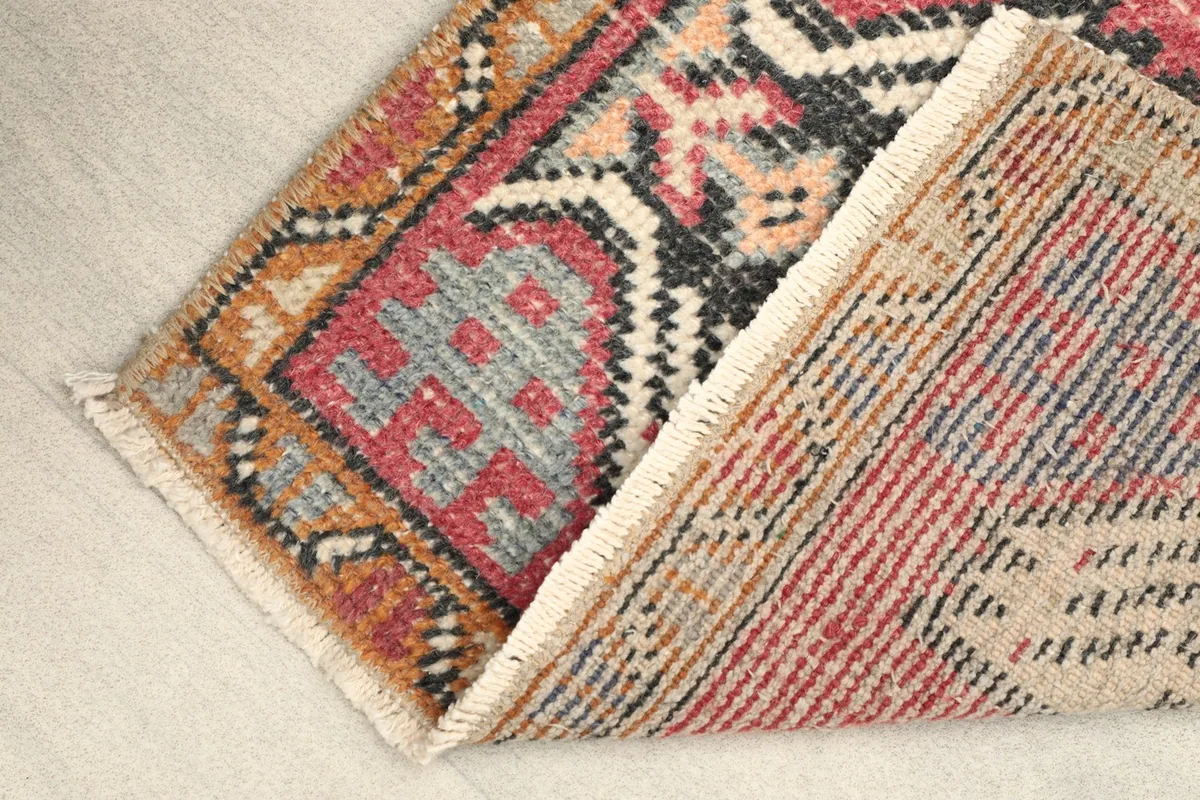 View of the rug's low pile and cotton foundation from the side, showing the backing.