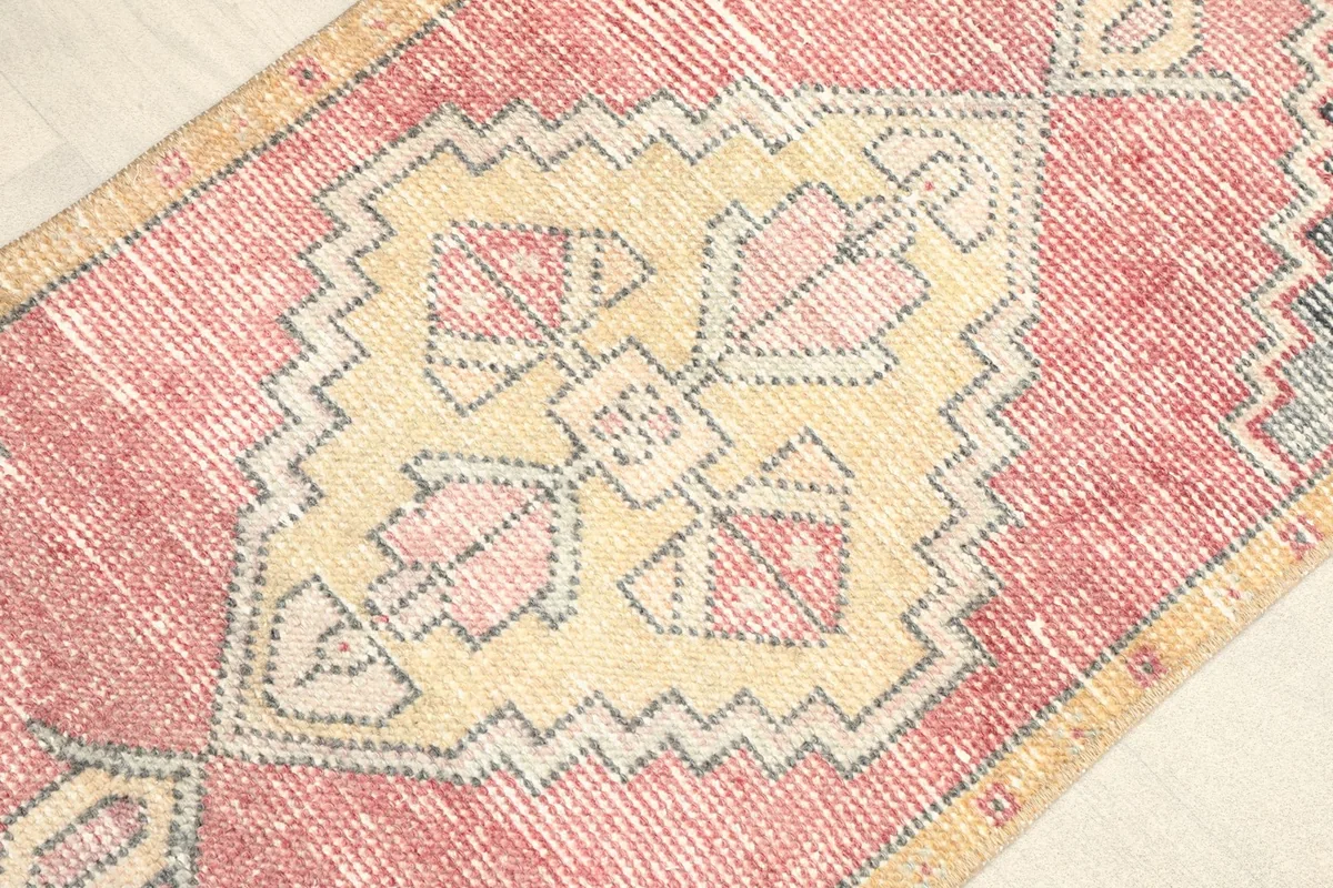 Angled view highlighting the central gold medallion and faded rose field of the rug.