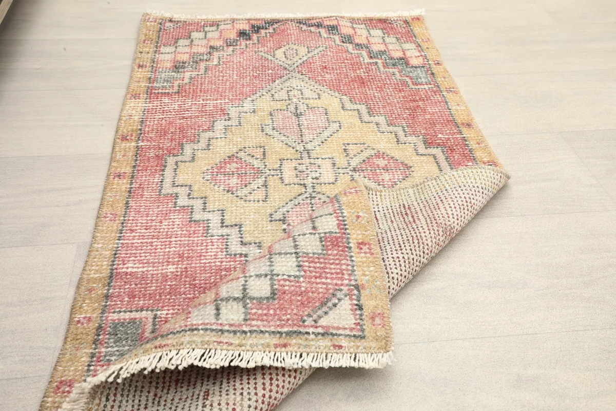 The vintage Anatolian rug partially folded, displaying its full pattern and backing.