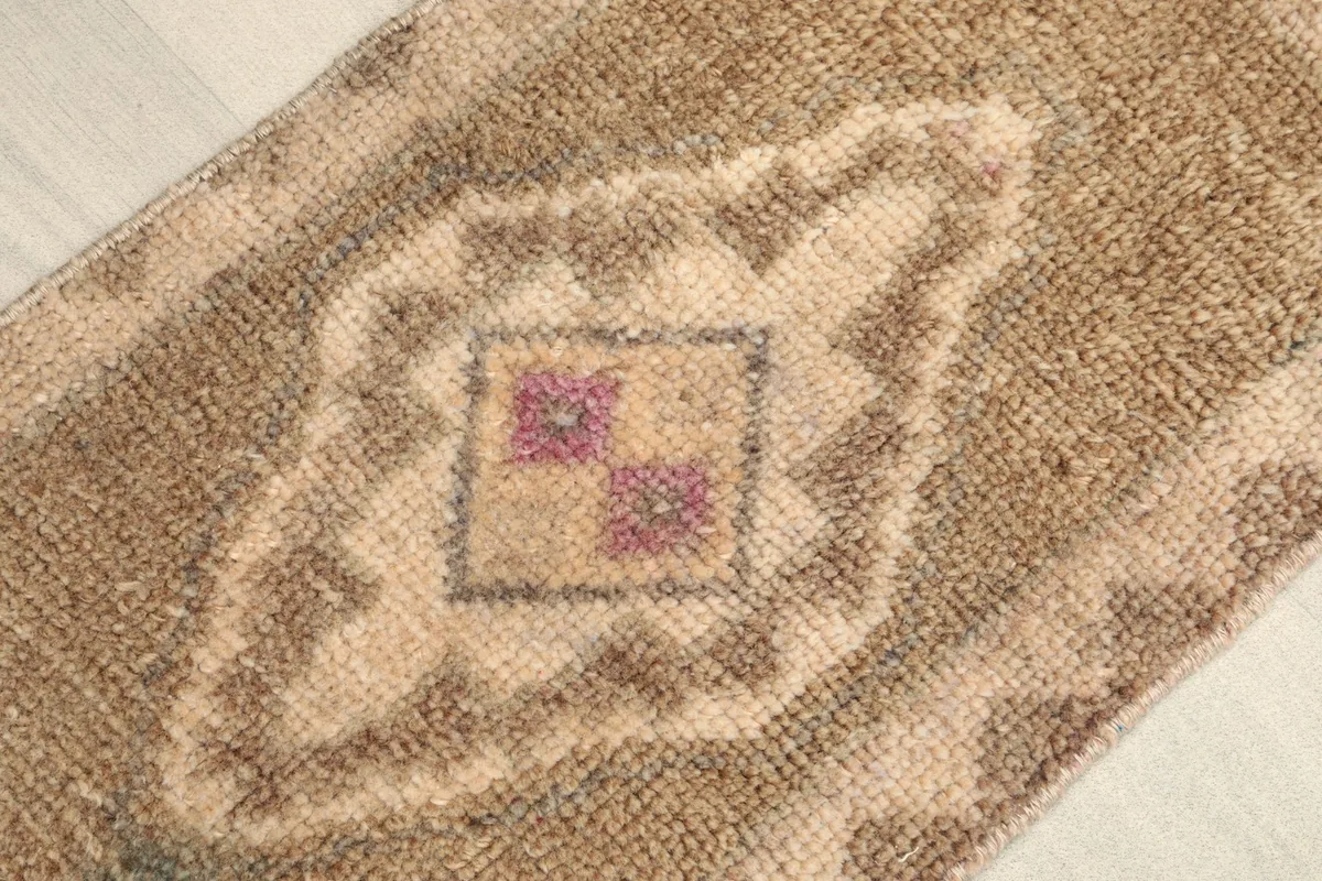 Close-up detail of the central tribal medallion with beige, tan, and rose colors.