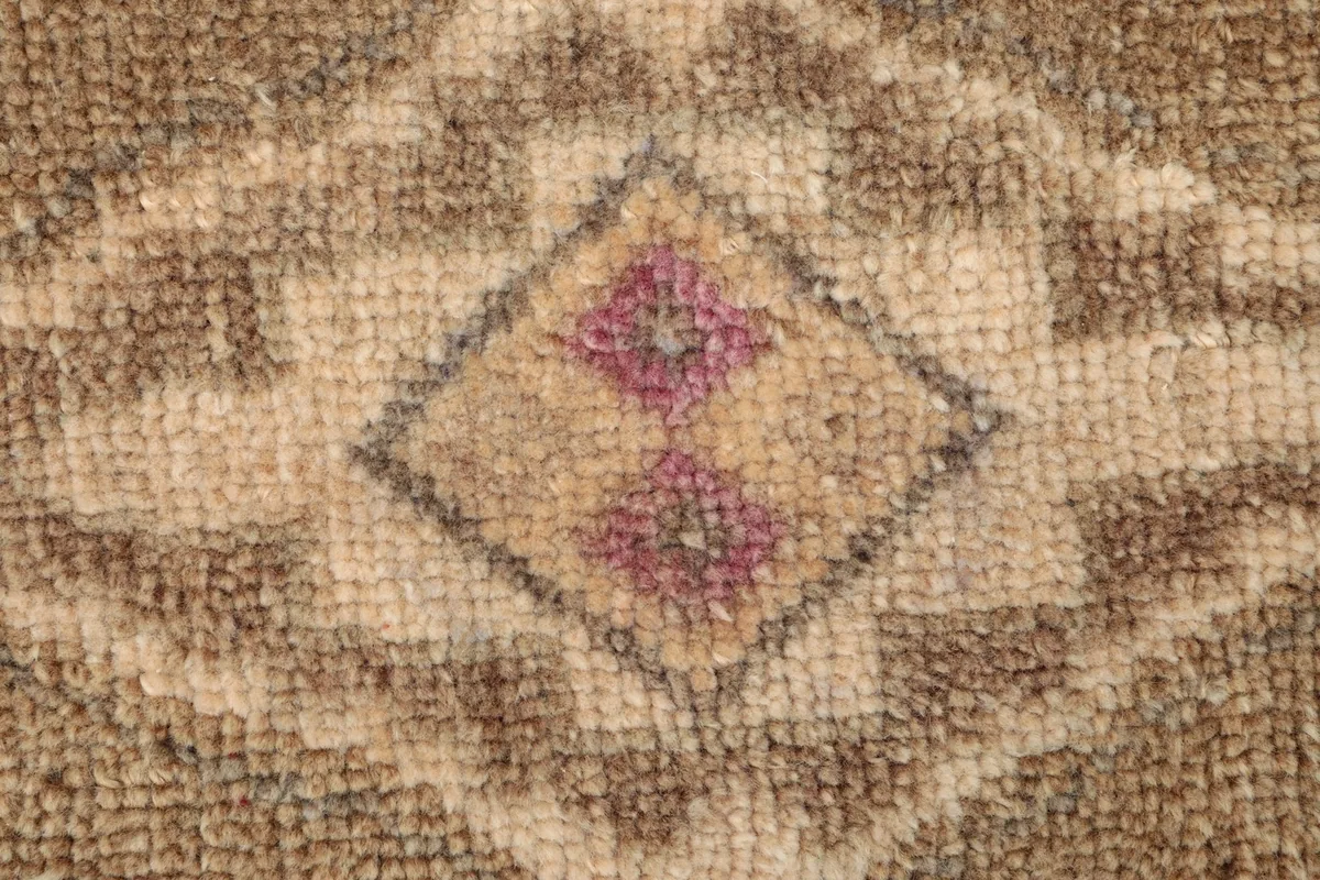 Detailed view of the rug's central motif, highlighting the hand-knotted texture and color variations.