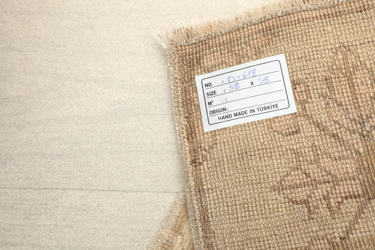 Back of the rug with a label indicating its origin as hand-made in Turkey and its dimensions.