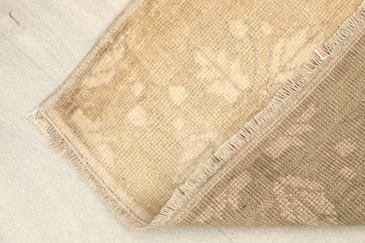Folded corner of the rug, revealing the wool pile on cotton foundation and fringe detail.