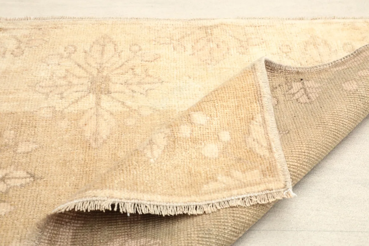 Partial fold of the rug, showing the reverse side and the hand-knotted construction.