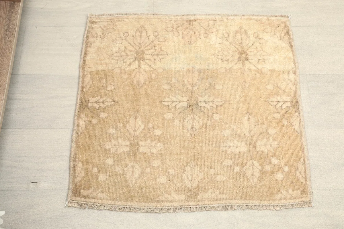 Overhead view showcasing the beige field and subtle tan floral and leaf patterns of the rug.