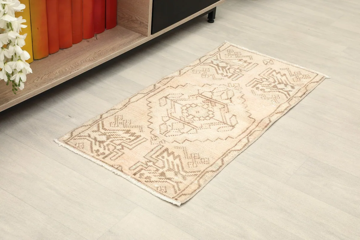 Angled view of the beige and brown tribal rug placed on a light floor next to a cabinet