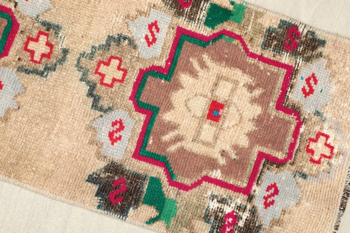 Close-up view of the center medallion and surrounding tribal patterns in beige, brown, red, green, and gray.