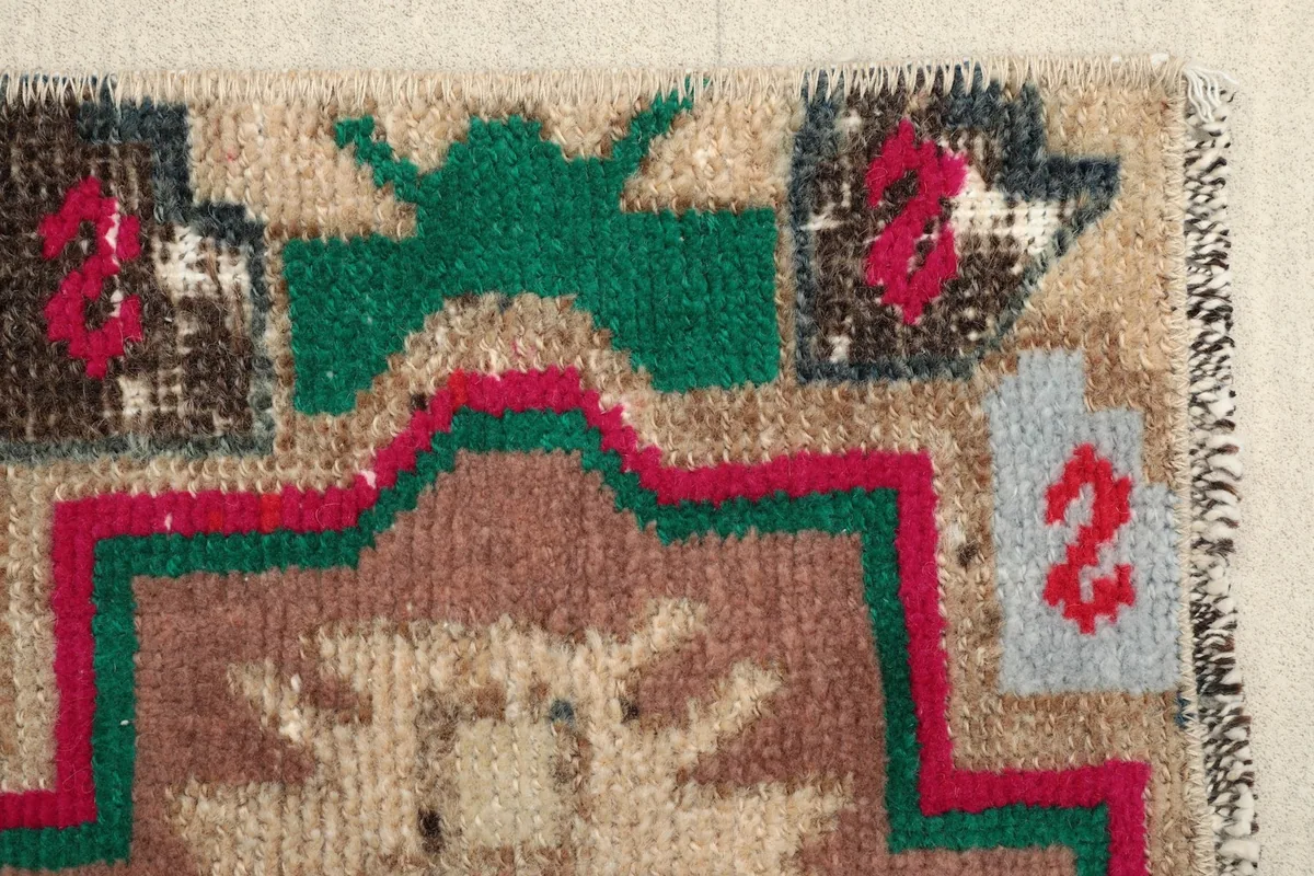 Close-up of a border section, revealing the green, red, and gray accents against the beige field.
