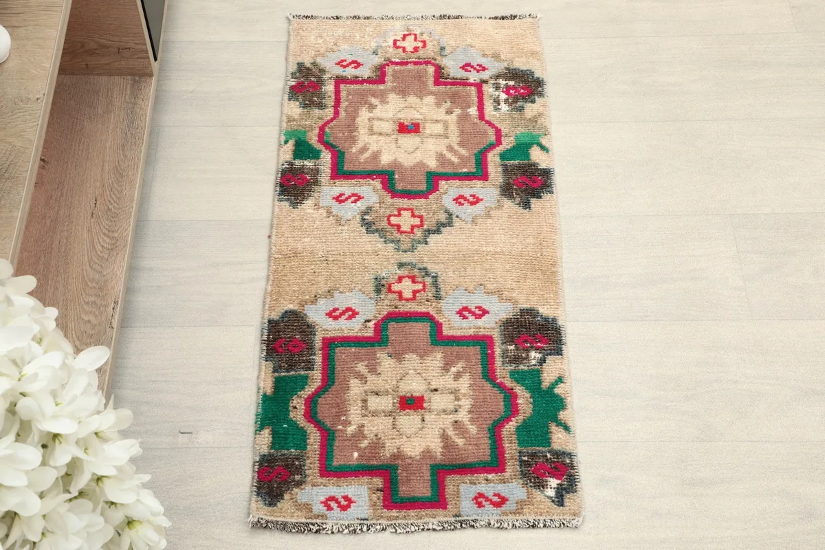 Overhead view of the vintage Anatolian doormat, highlighting its beige field and colorful tribal motifs.