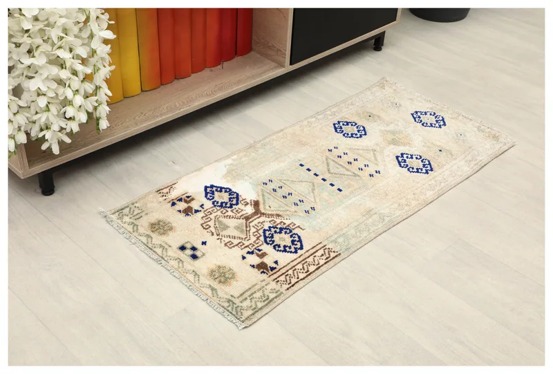 Top view of the 1'7" x 3'5" ivory tribal geometric doormat on a light floor.