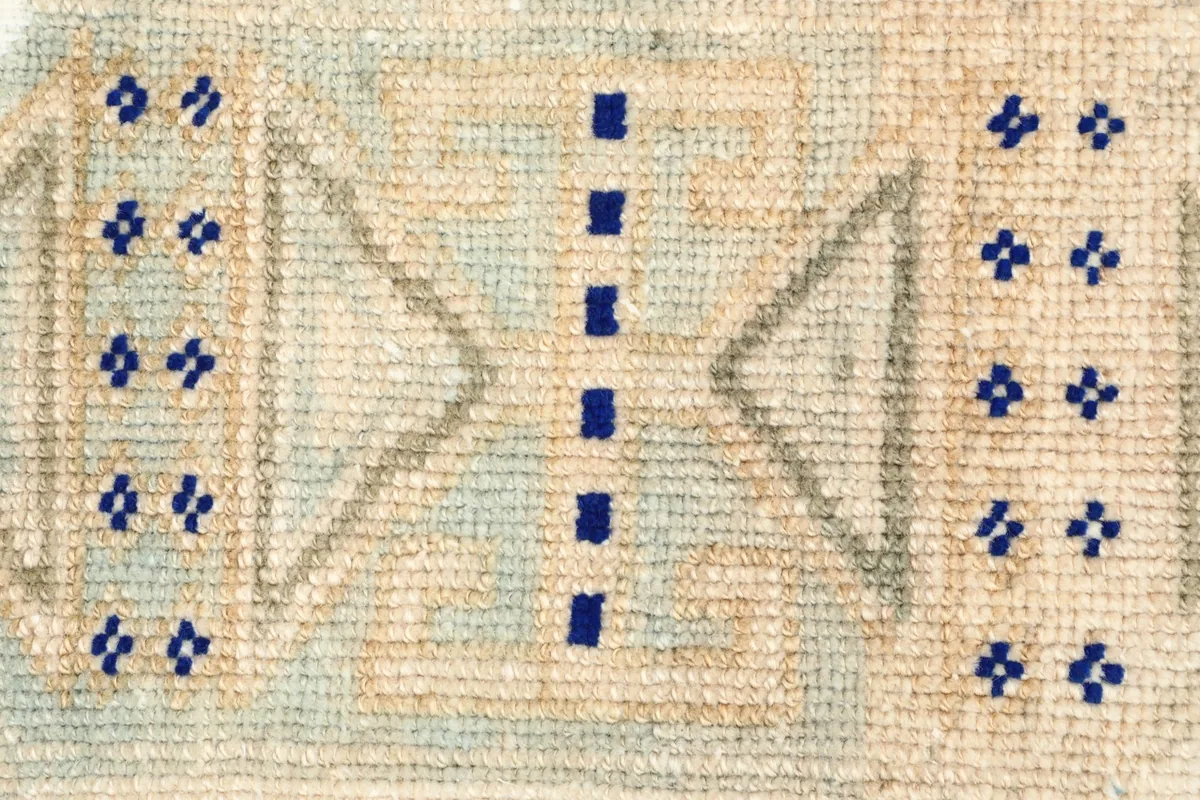 Close-up detail of the hand-knotted geometric motifs and color variations in the pile.