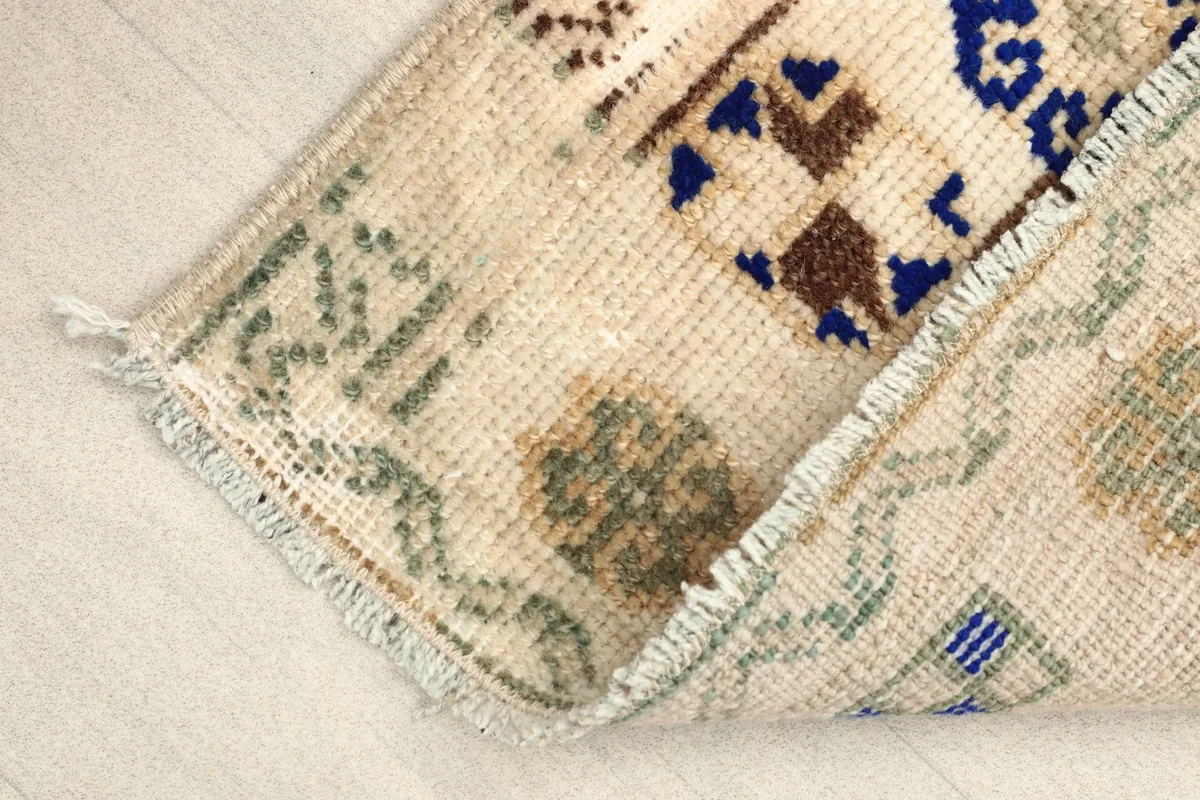 Angled view of the doormat with a corner folded, showing the back and the fringe.
