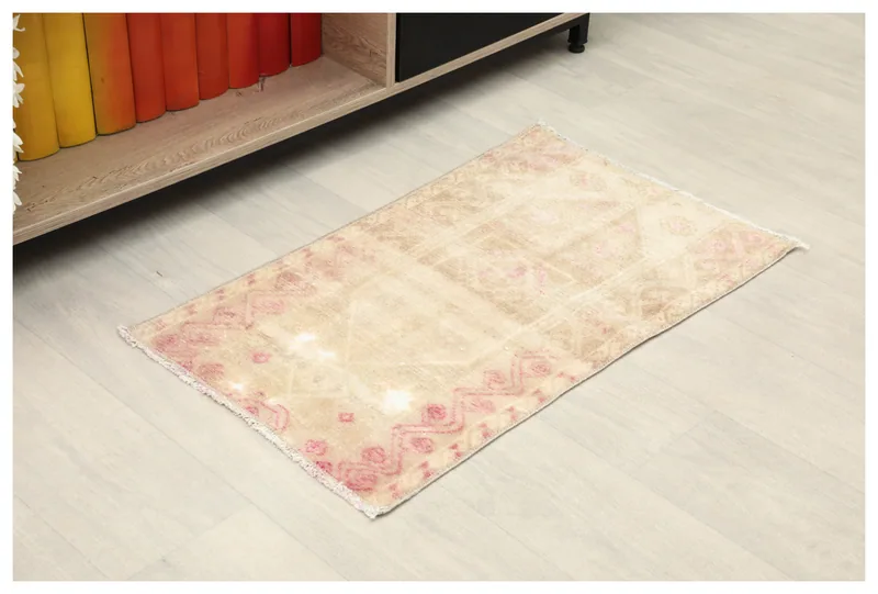 Full top view of the beige and rose geometric vintage Anatolian rug on a white background.