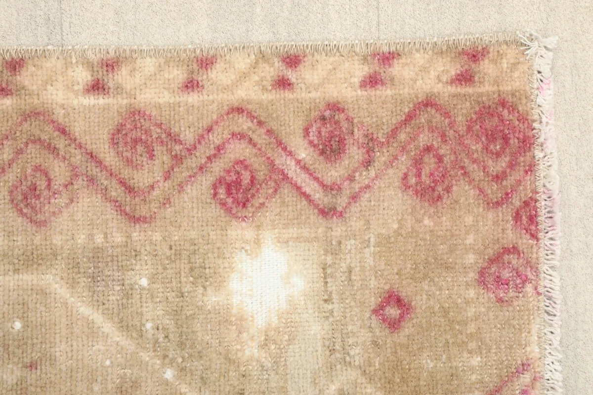 Detail of the side border with a wavy rose geometric pattern against the beige field.
