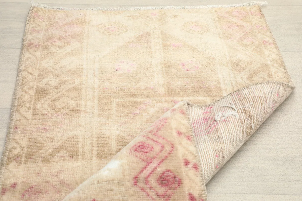 View showing the low wool pile and the vintage character of the rug, with a corner folded.