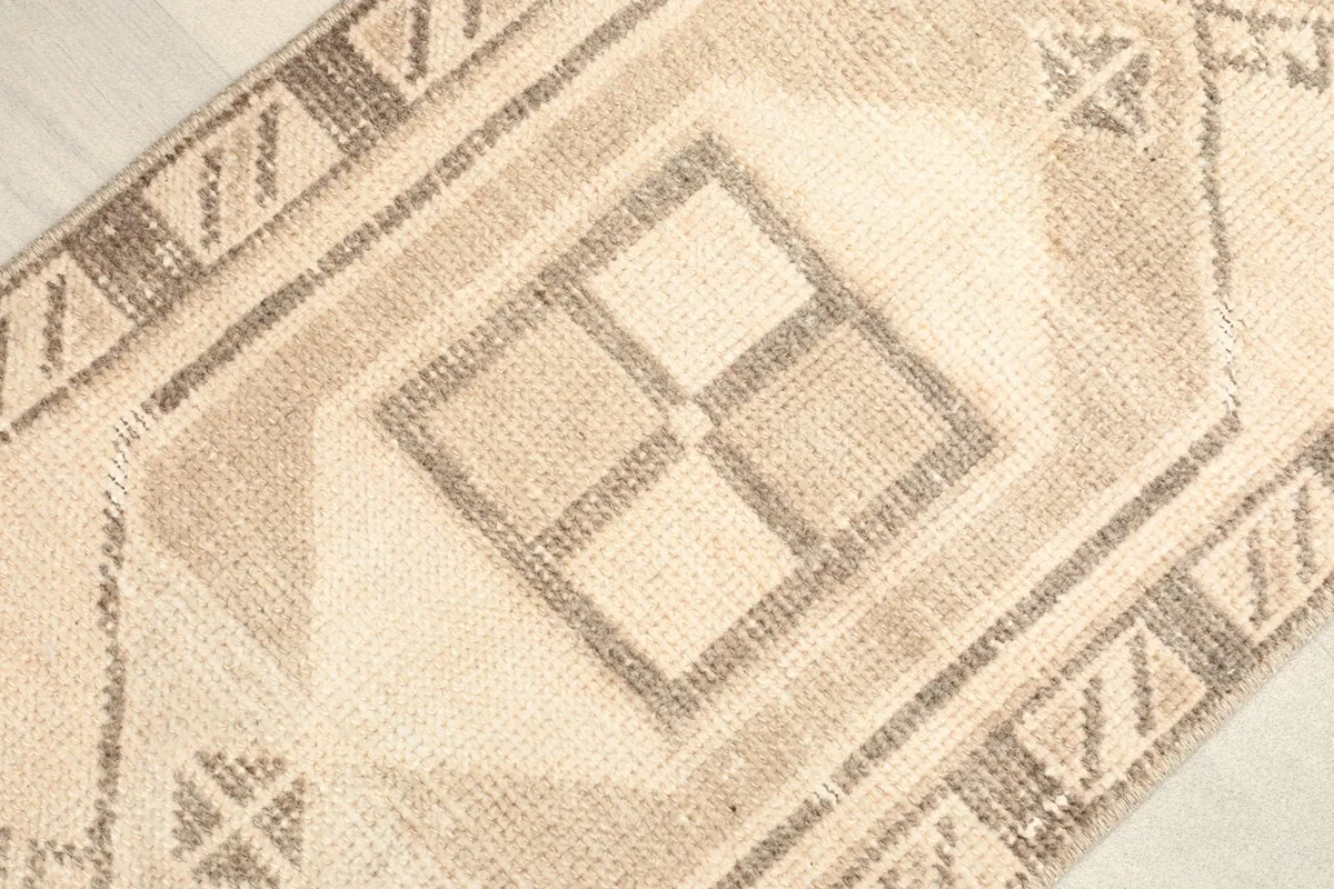 Close-up of the central brown geometric motif and surrounding cream field of the rug.