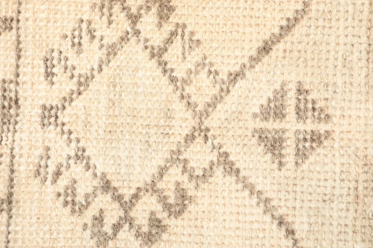 Detailed view of the hand-knotted wool pile and tribal patterns in brown and beige tones.