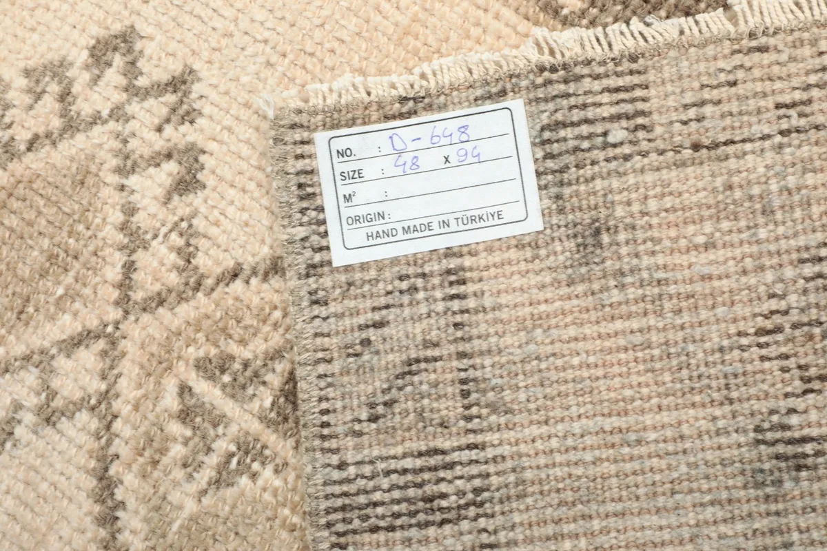 Back of the rug showing the hand-knotted construction and a product label with size information.