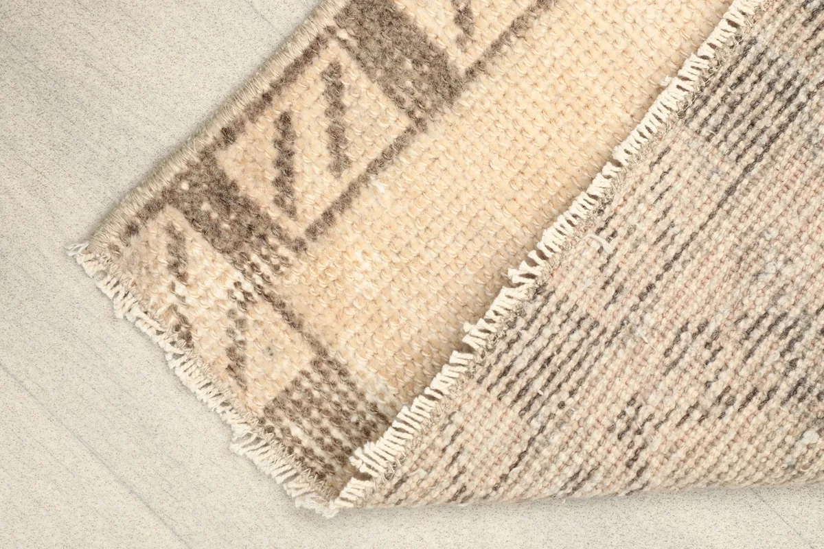 Folded corner of the rug revealing the sturdy cotton foundation and the back of the weave.
