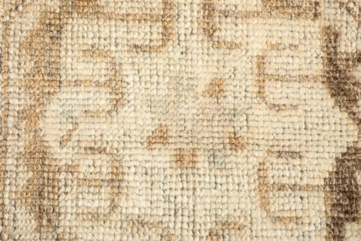 Detailed view of the hand-knotted wool pile, showing the intricate beige and brown coloring