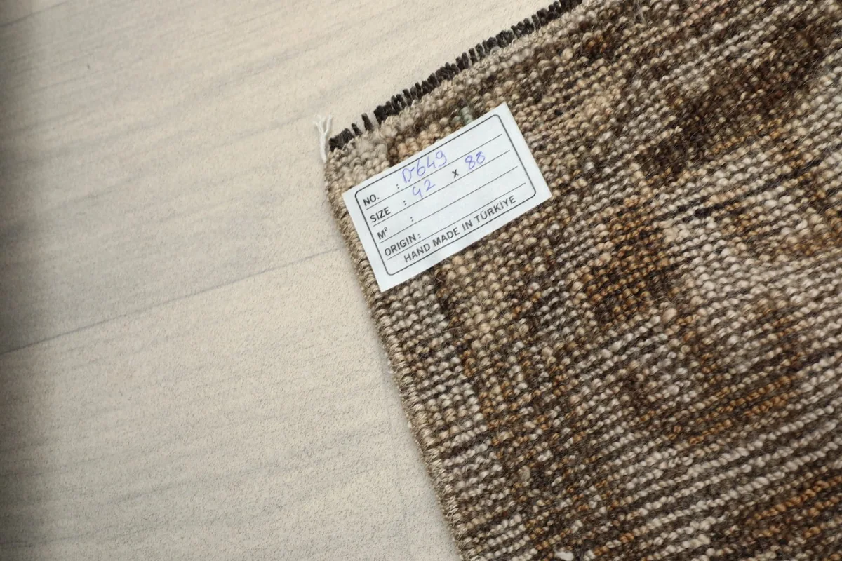 Backside of the rug with its care label, showing the tight hand-knotted cotton foundation