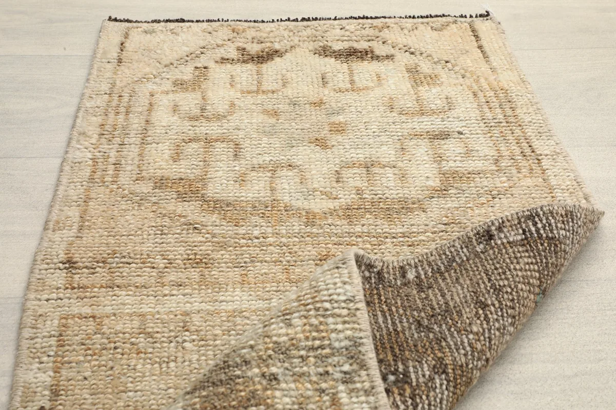 Partial fold of the rug revealing the reverse side texture and the front's geometric design