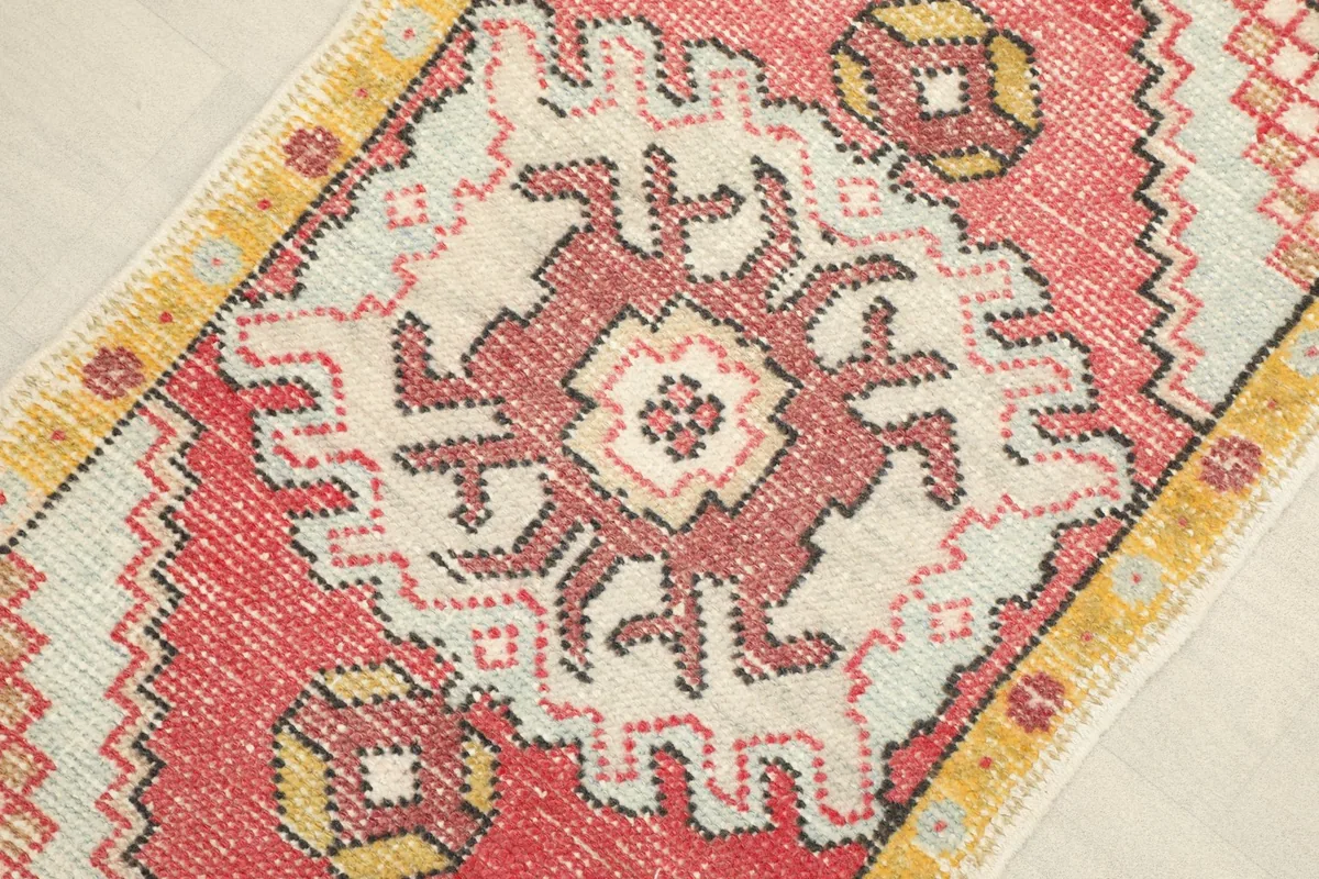 Close-up detail of the central ivory geometric medallion against the rose field with yellow accents.