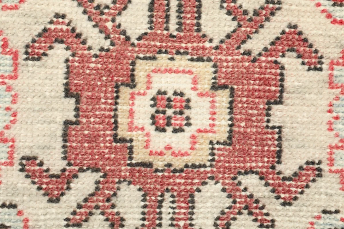 Tight detail of the hand-knotted wool pile, showing the intricate weaving and color variations in the medallion.