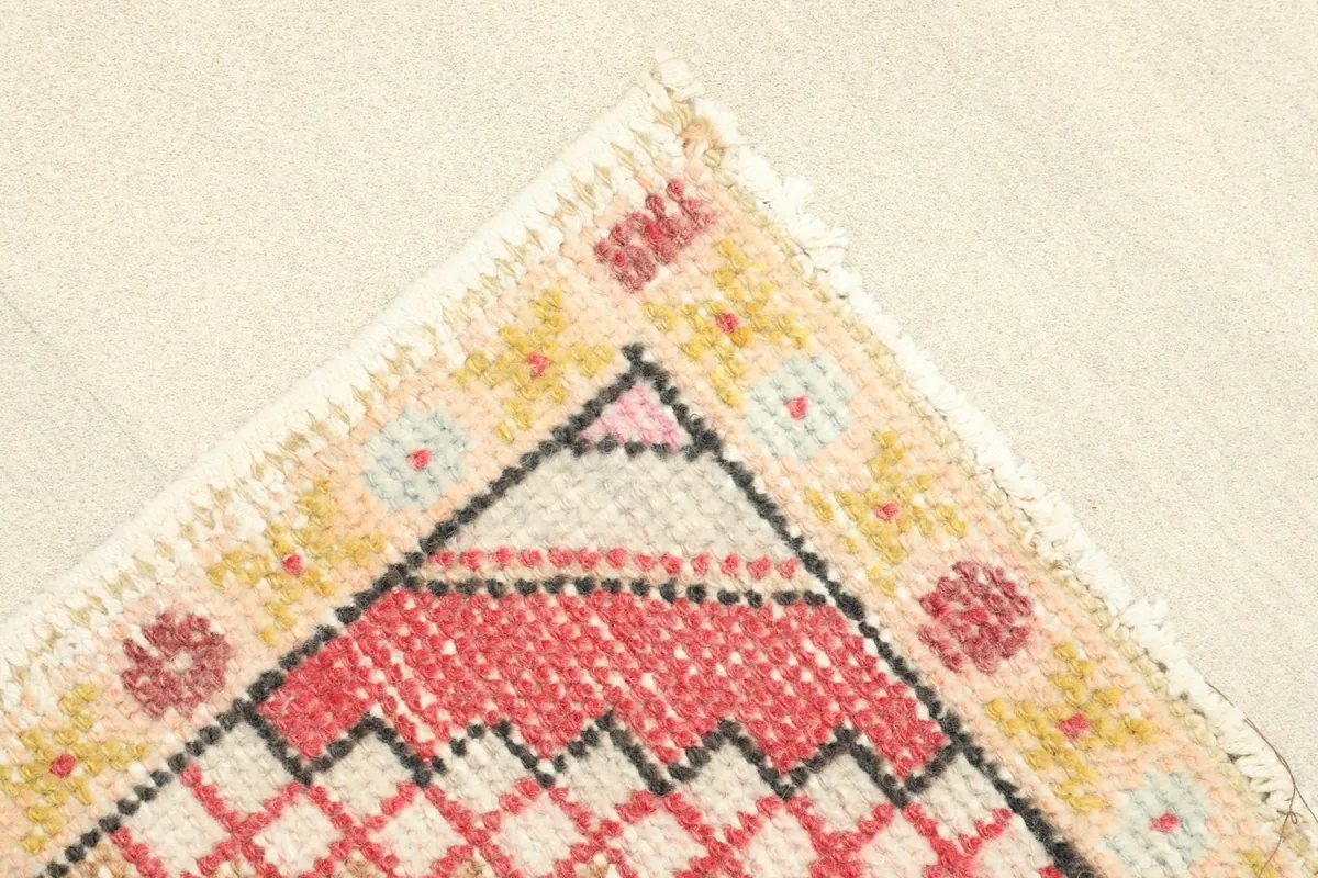 Corner view of the rug, highlighting the yellow border with small floral motifs and the fringe.