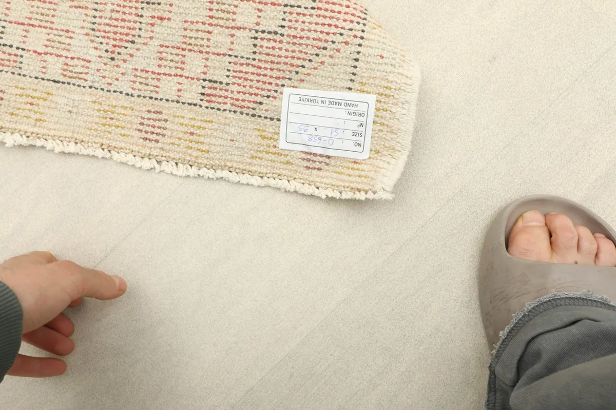 Rug label visible on the back, next to a foot for scale, showing the mini size.