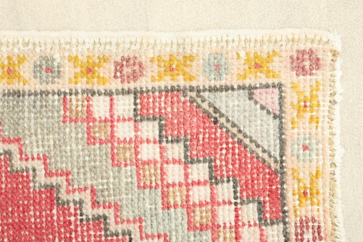 Close-up of the rug's border with small yellow and rose patterns