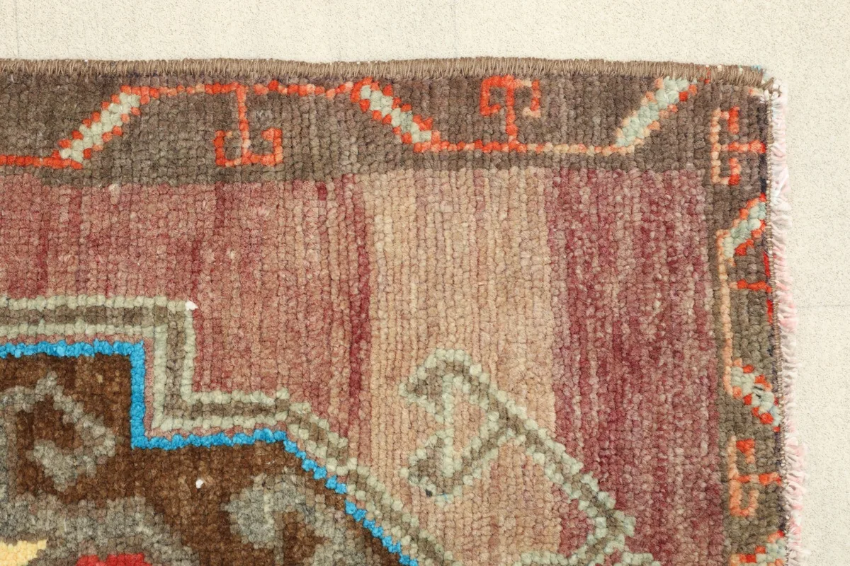 Close-up of the short side border and the variegated beige and red field.