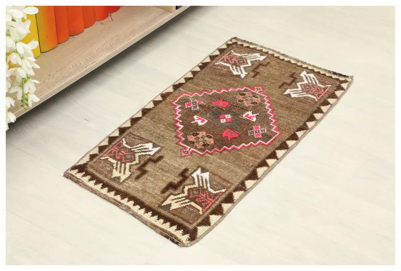 Full top view of the brown vintage Anatolian doormat with tribal patterns on a white background