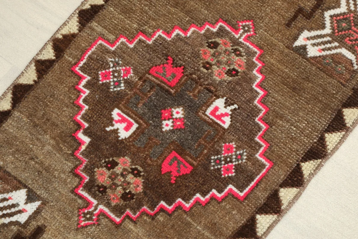 Close-up detail of the central pink and brown geometric medallion on the rug