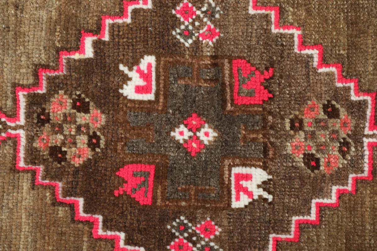 Detailed view of the intricate pink, brown, and ivory patterns within the rug's central design