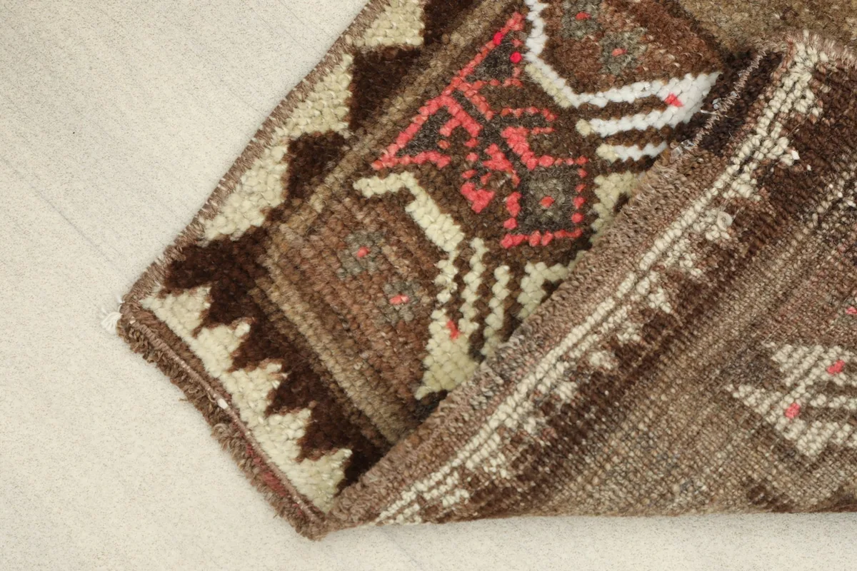 Folded section of the rug, revealing the texture of the low wool pile and cotton foundation