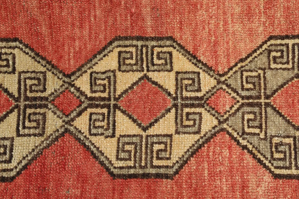 Detailed view of the intricate hand-knotted geometric design and color variations in the rug's pile.