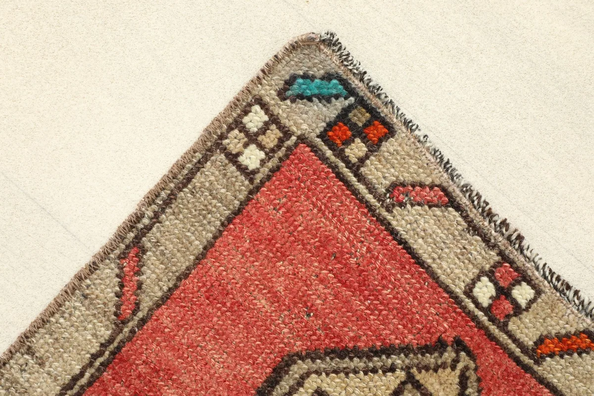 Corner detail showing the gray border with small accent colors and the rug's hand-finished edge.