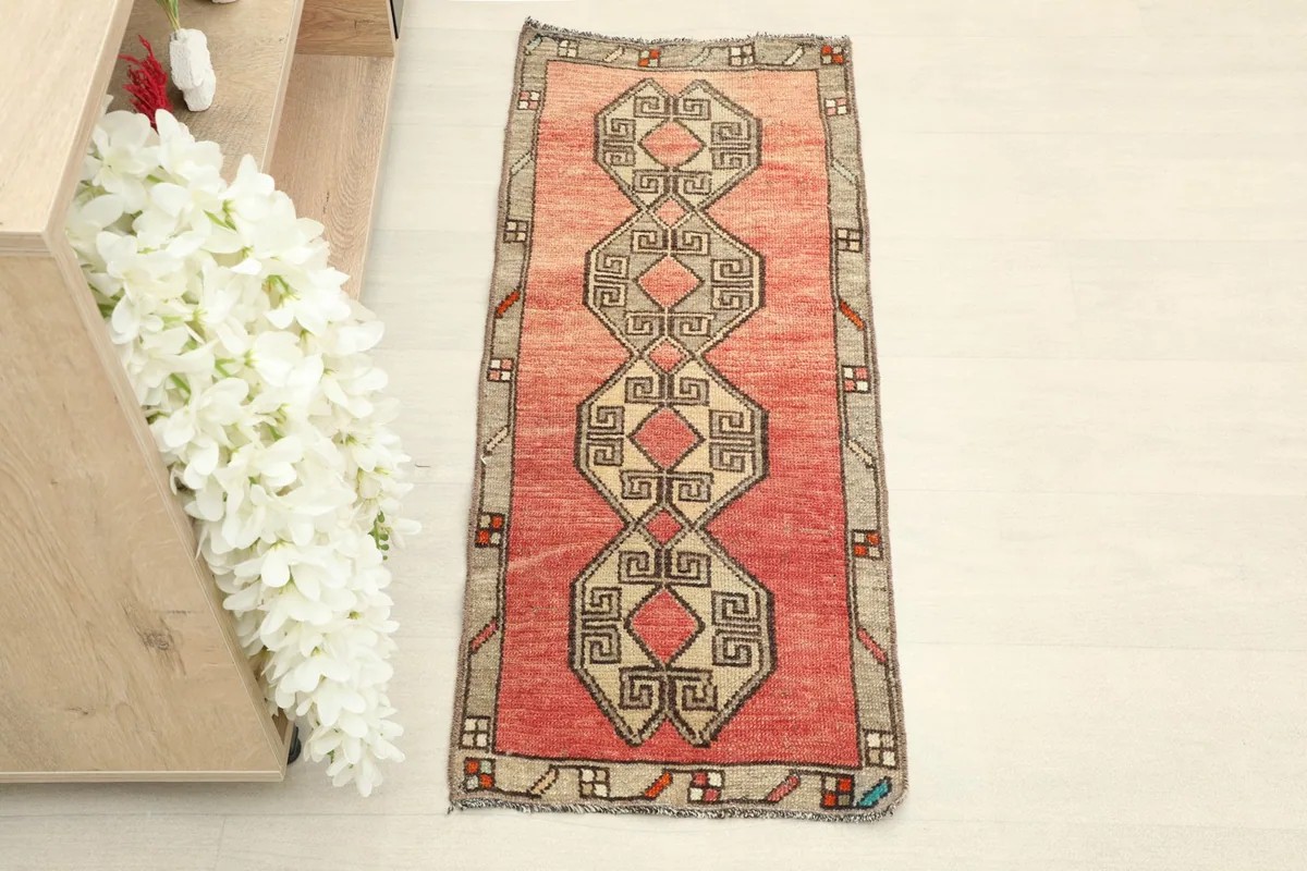 Overhead view of the hand-knotted wool rug, highlighting its rose field and central geometric motif.