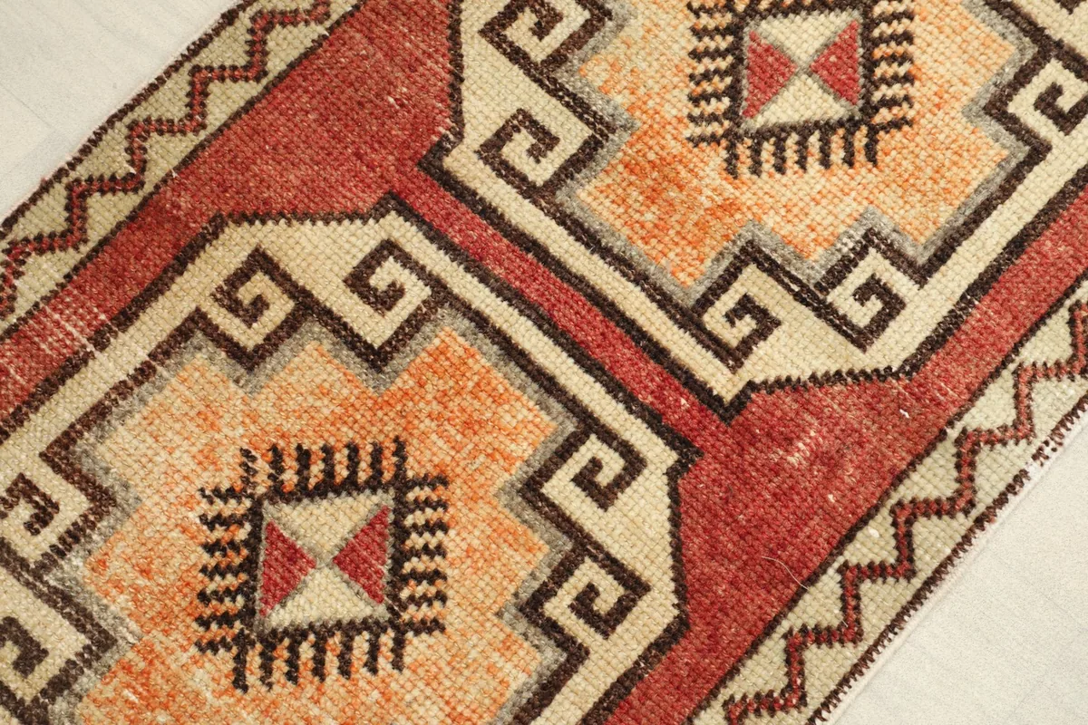 Angled view highlighting the rust and orange colors and the distinct geometric patterns of the rug.