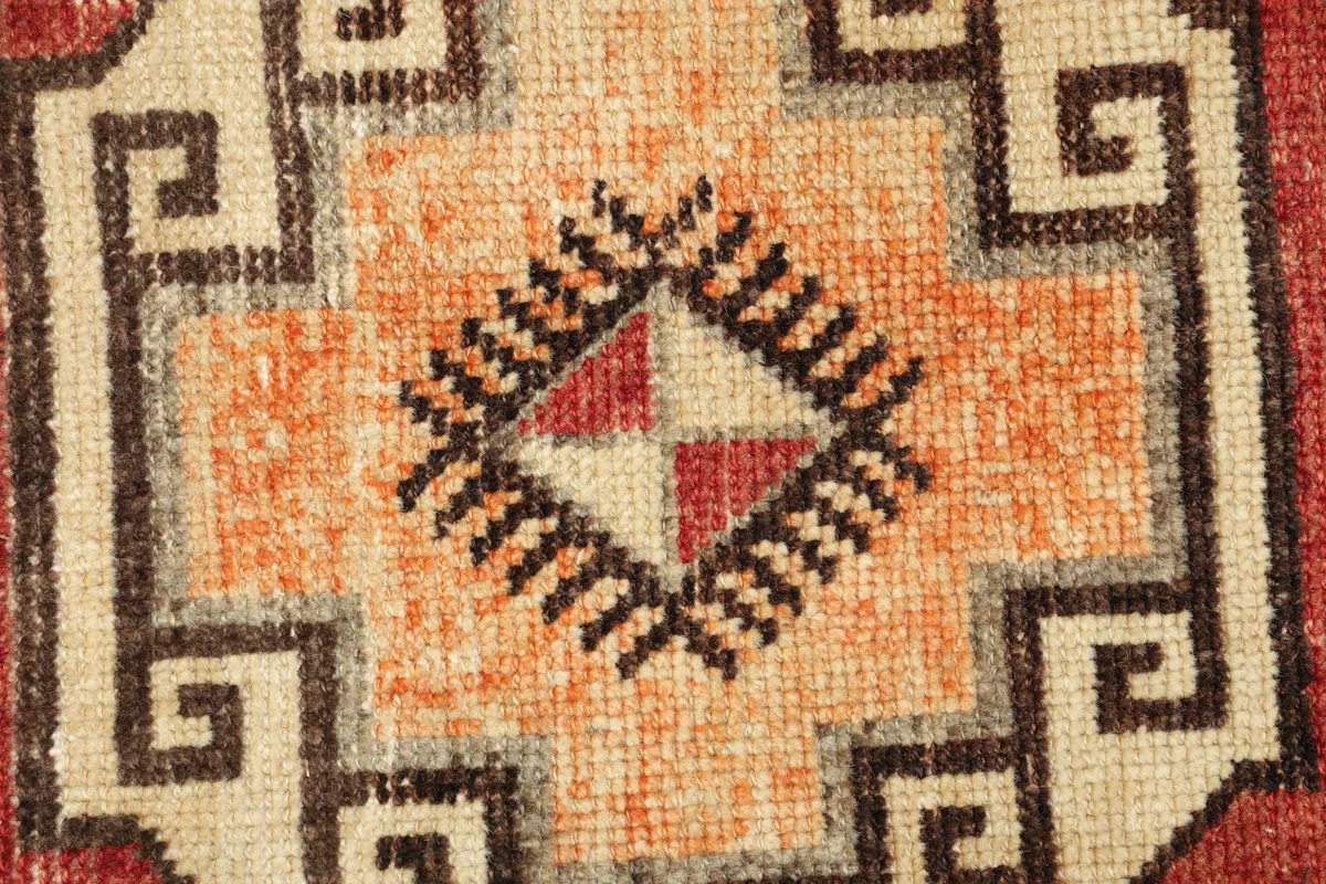 Close-up detail of a central beige and orange geometric motif with brown outlines.