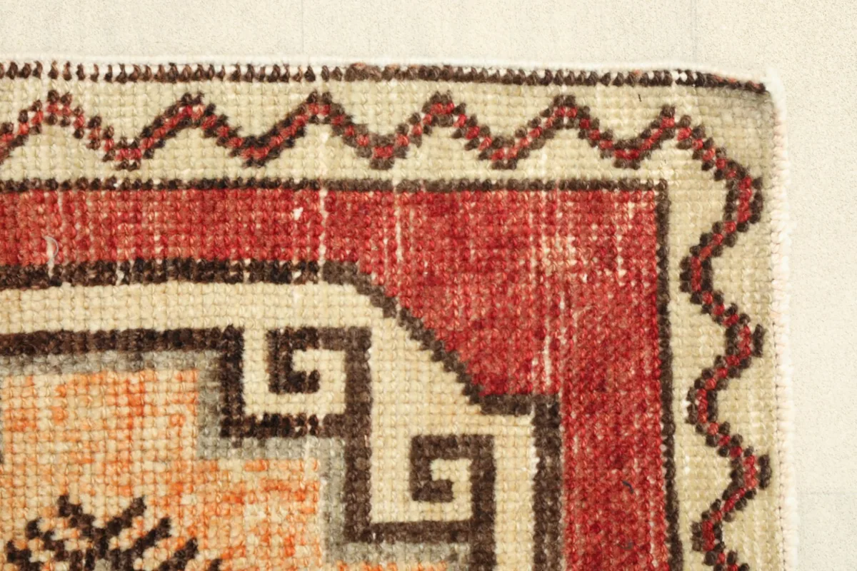 Close-up of a corner, focusing on the intricate beige and rust border designs.