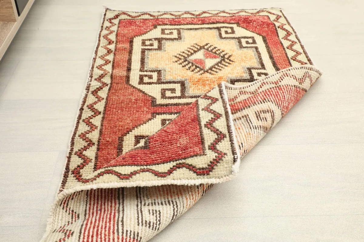 The vintage rug partially folded, showing both the front design and the back weaving.